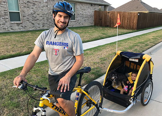 Doctor Aguilar riding a bike with is daughter and dog