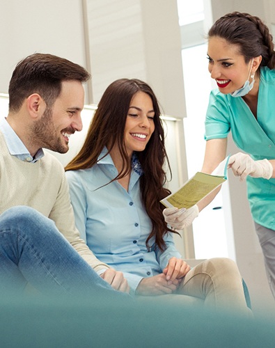 Dental assistant showing smiling couple form