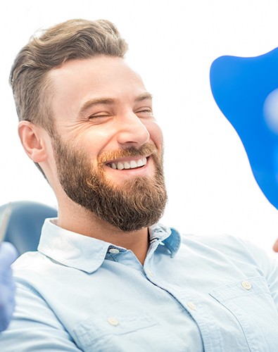 Man in dental office looking at smile in mirror