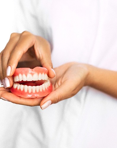 Closeup of Denton dentist holding dentures in their hands