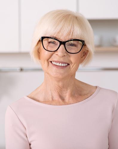 Senior woman with glasses smiling in kitchen 