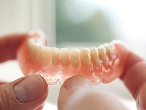 Close-up of hands holding a denture in Denton, TX