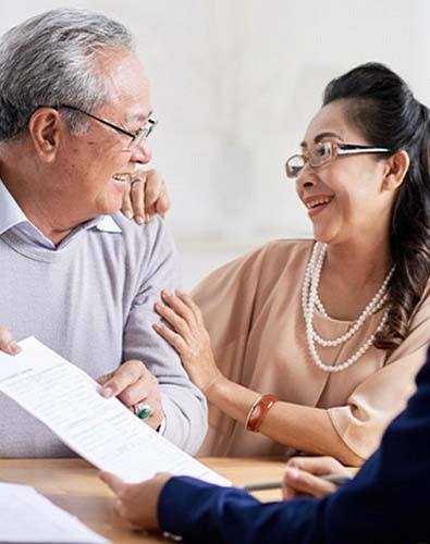 Smiling couple with paperwork learn about the cost of dental emergencies