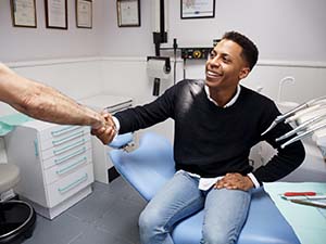dentist and patient shake over the cost of dental emergency treatment