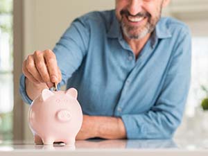 Man making emergency dental care affordable with piggy bank