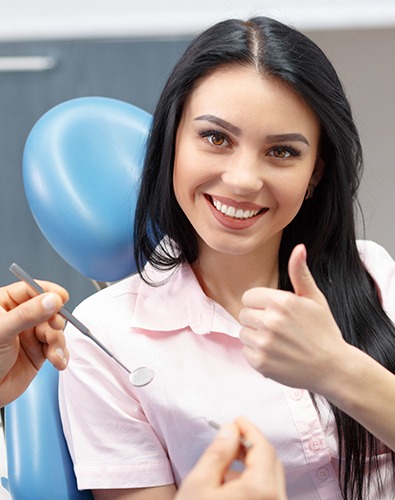 Woman in dental chair giving thumbs up