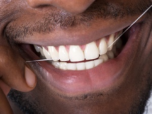 closeup of man flossing his teeth