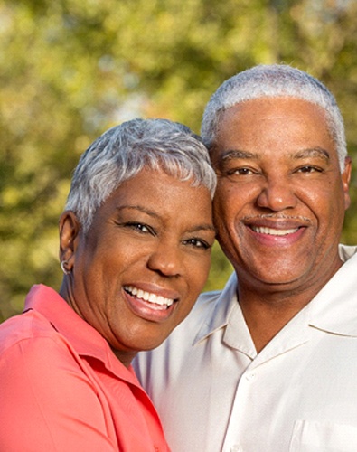 Candidates for implant dentures in Denton smiling outside