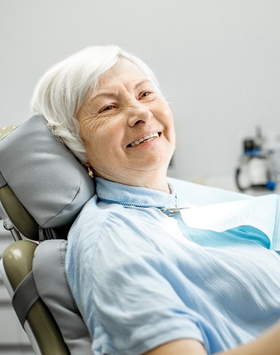 An older woman admiring the implant denture in her mouth