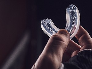 A hand holding a clear plastic mouthguard