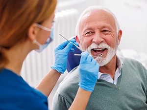 An older man receiving a dental checkup from his dentist