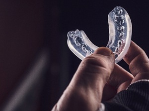 Female patient with handheld mirror after receiving dental implants in Denton, TX