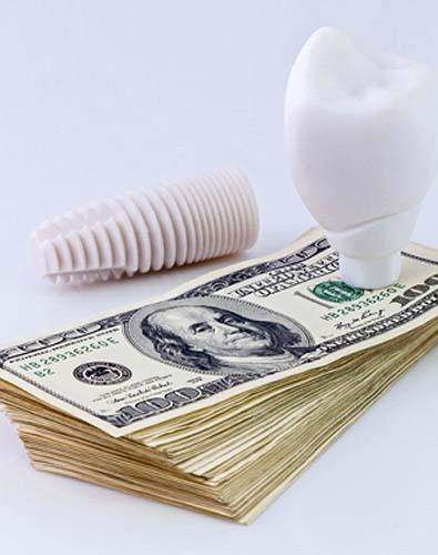 Model implant and money representing cost of dental implants in Denton