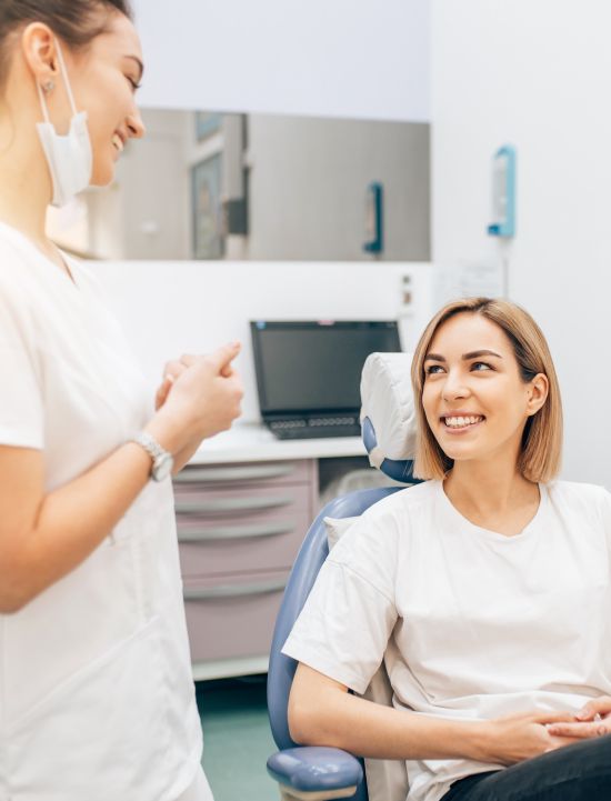 Smiling woman in dental chair talking to dental team member