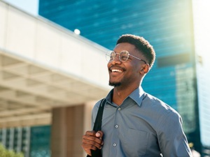 Man with glasses smiling while walking to work