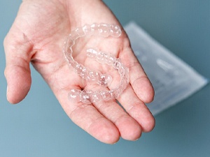 person holding two clear aligners