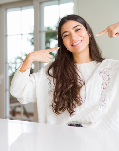 Woman pointing at her smile from kitchen table