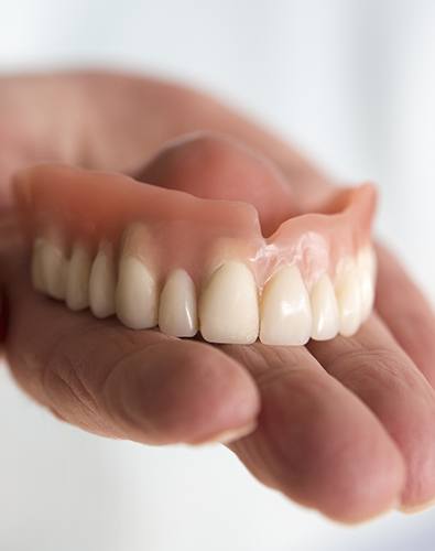 Hand holding a full denture