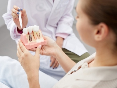 woman looking at dental implant model