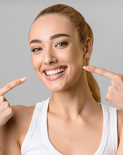 Woman pointing to her whitened smile