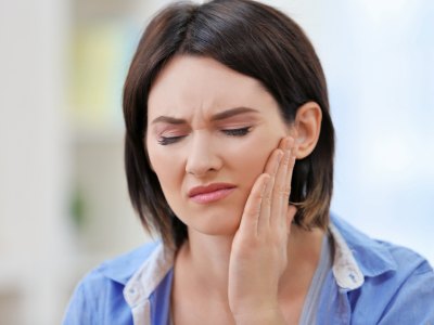 Woman in need of restorative dentistry holding jaw