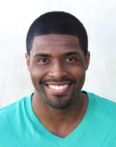 A young male wearing a teal t-shirt and smiling after seeing his dentist in Denton