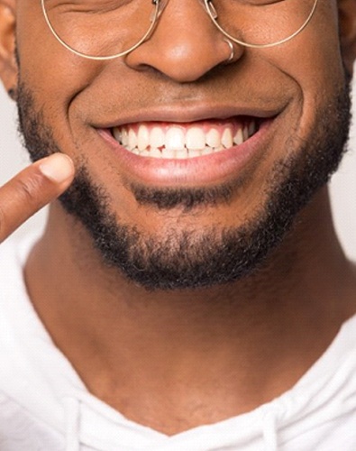 close up of a man pointing to his smile