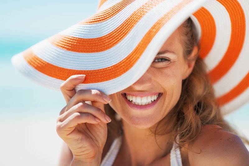 Woman with orange and white striped hat smiling on beach