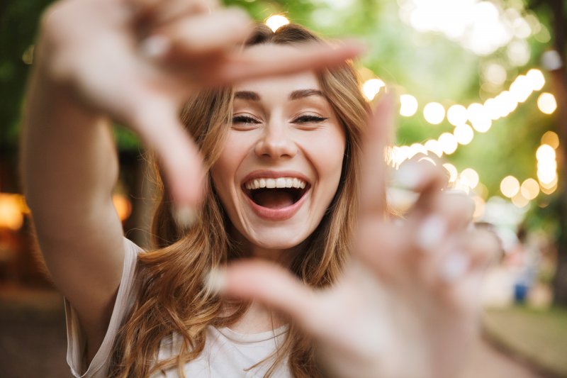 young woman smiling through frame made with fingers