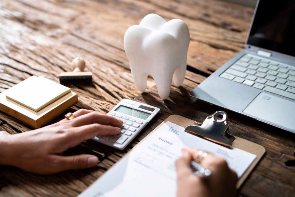 Patient working on dental insurance paperwork next to laptop