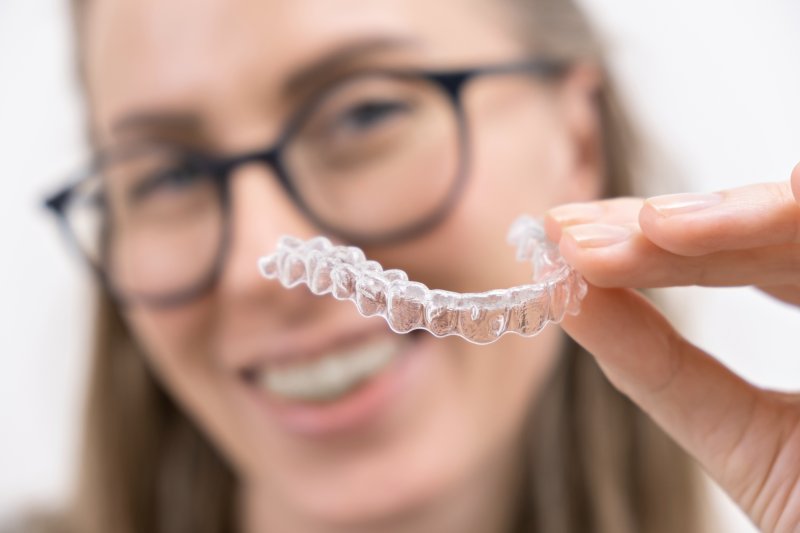 woman holding Invisalign aligners in Denton