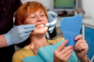 woman smiling in the mirror at her new dental implants