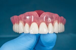 Close-up of hand holding full denture. 
