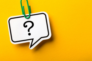 A paperclip holding a question mark that’s written on paper